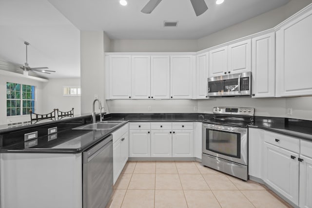 kitchen with sink, stainless steel appliances, light tile patterned floors, kitchen peninsula, and white cabinets