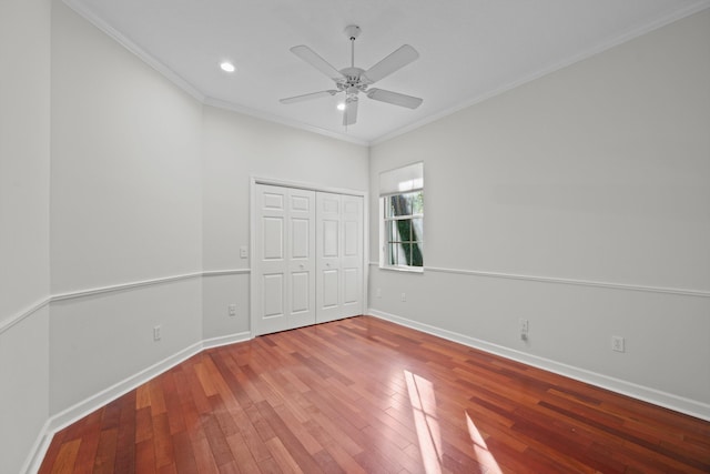 unfurnished bedroom with ceiling fan, a closet, ornamental molding, and hardwood / wood-style flooring