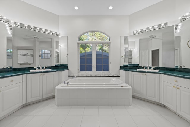 bathroom with tile patterned flooring, vanity, ceiling fan, and tiled tub