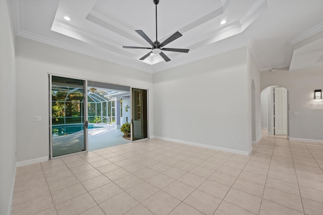 tiled empty room with ceiling fan, ornamental molding, and a tray ceiling