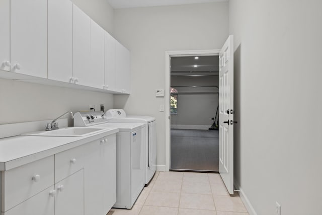 laundry area featuring washing machine and dryer, light tile patterned floors, and cabinets