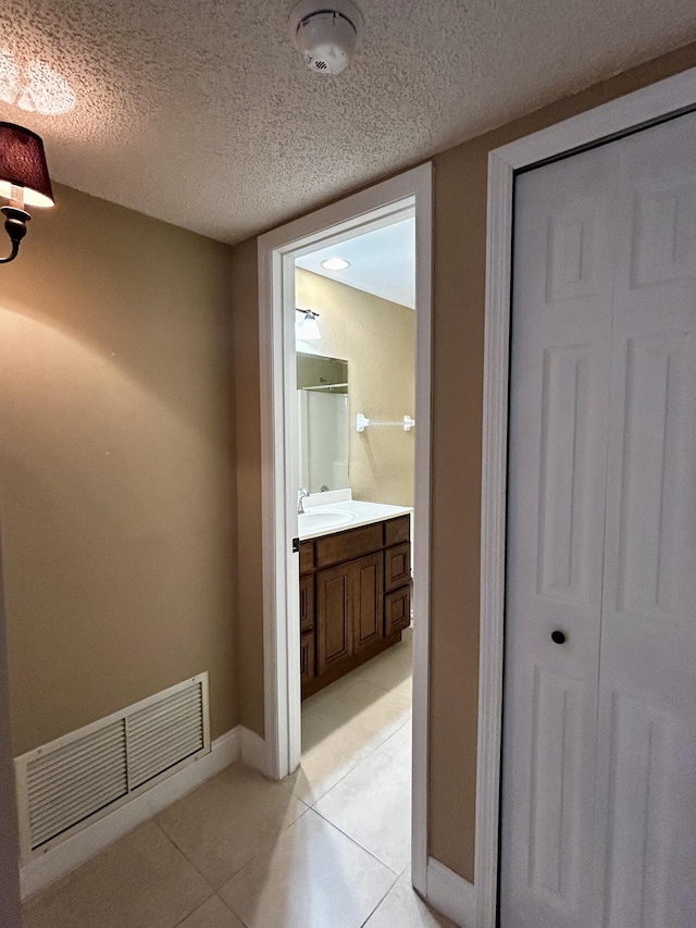 interior space with vanity, a textured ceiling, and tile patterned floors