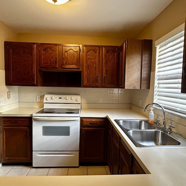 kitchen featuring light tile patterned flooring, backsplash, white range with electric cooktop, and sink