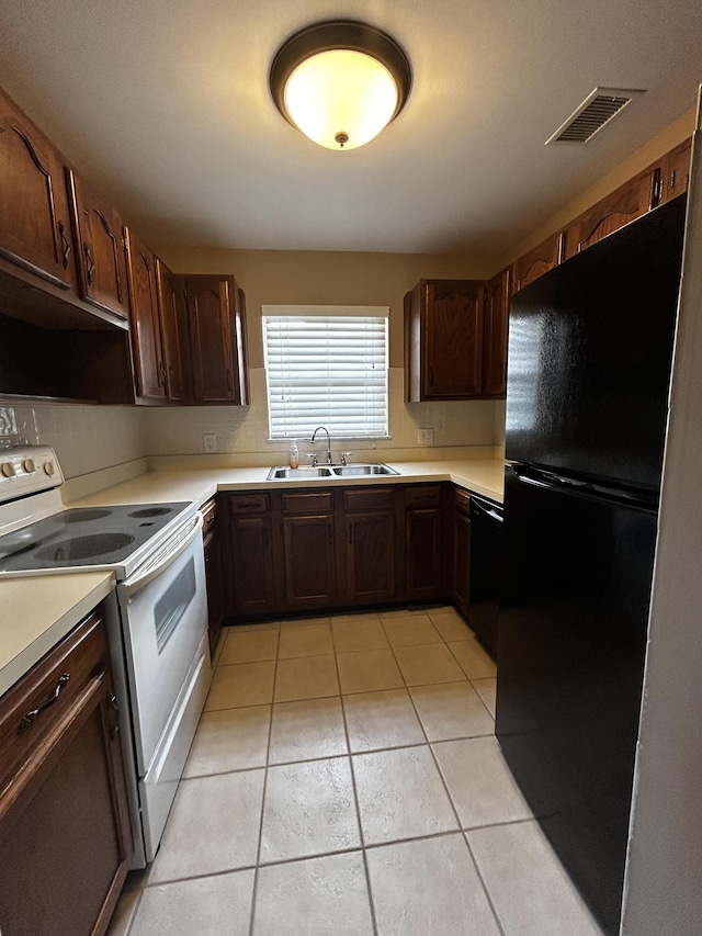 kitchen with light tile patterned floors, sink, dark brown cabinets, and black appliances