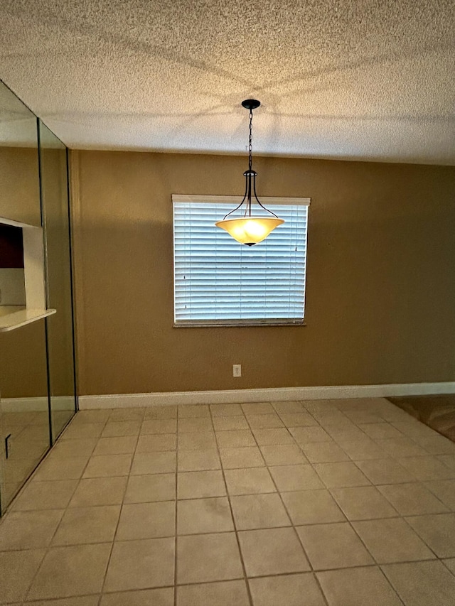 unfurnished dining area featuring plenty of natural light, tile patterned flooring, and a textured ceiling