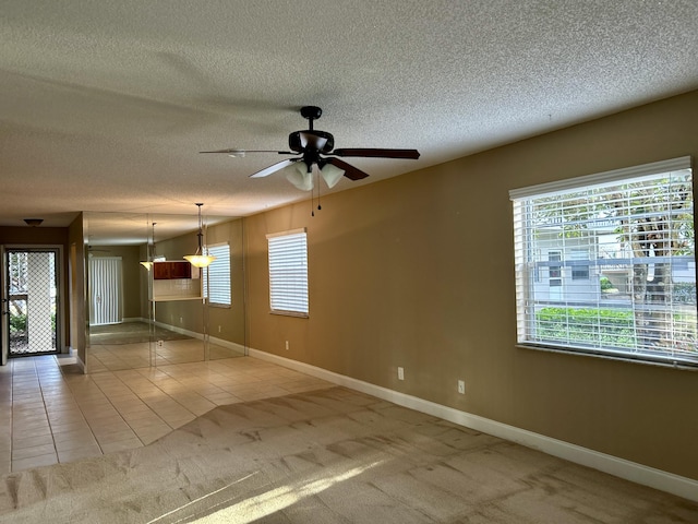 carpeted spare room featuring a textured ceiling and ceiling fan