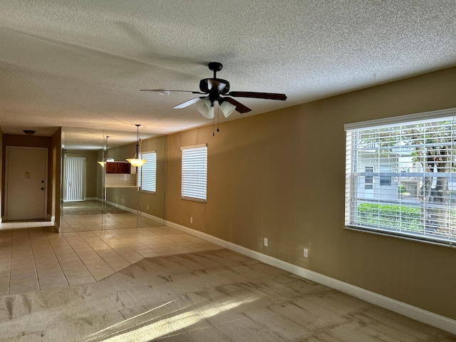 empty room with ceiling fan, light colored carpet, and a textured ceiling