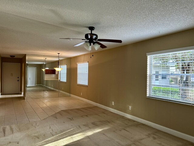 tiled spare room with a textured ceiling and ceiling fan