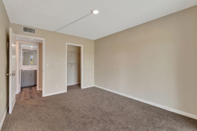 unfurnished bedroom with dark colored carpet, a textured ceiling, and a closet