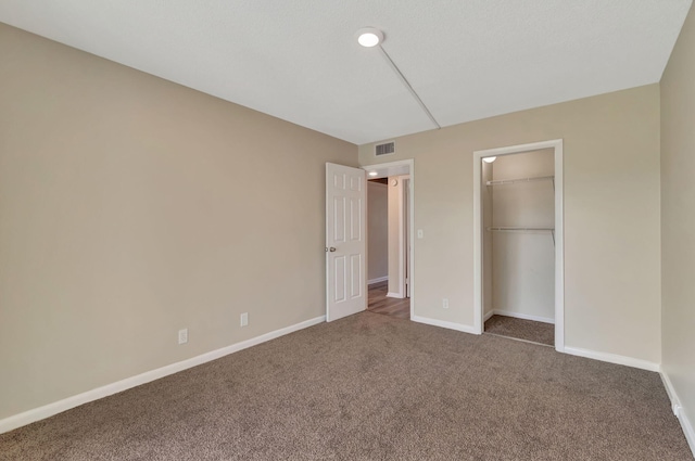 unfurnished bedroom featuring carpet flooring, a walk in closet, and a closet