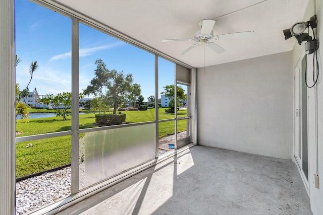 unfurnished sunroom featuring ceiling fan and a water view