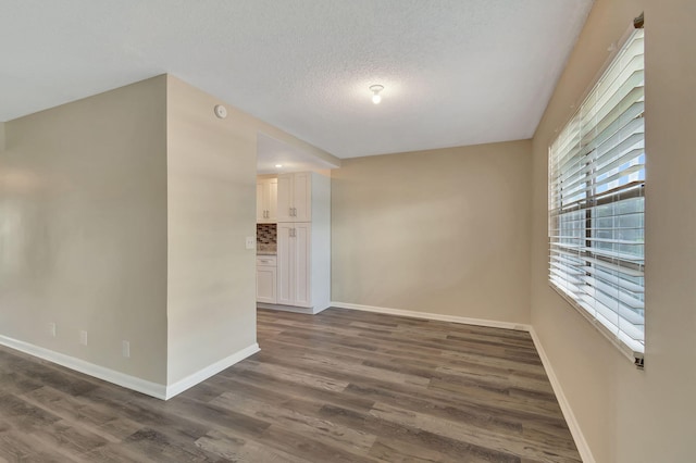 unfurnished room featuring a textured ceiling and dark hardwood / wood-style flooring