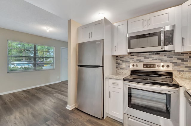 kitchen featuring light stone countertops, appliances with stainless steel finishes, white cabinetry, and hardwood / wood-style floors