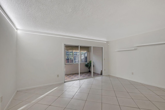 empty room featuring light tile patterned flooring and a textured ceiling