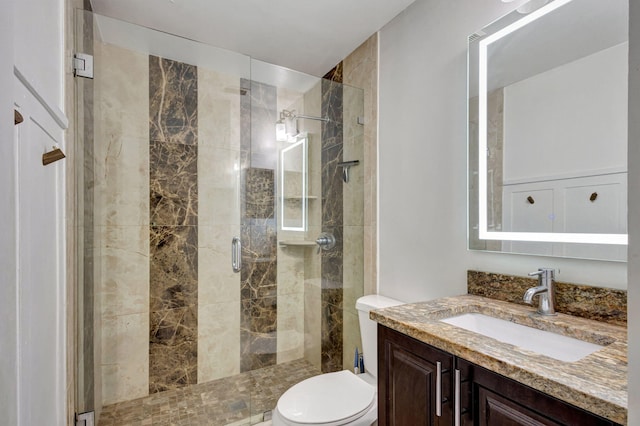 bathroom featuring vanity, toilet, and a shower with door