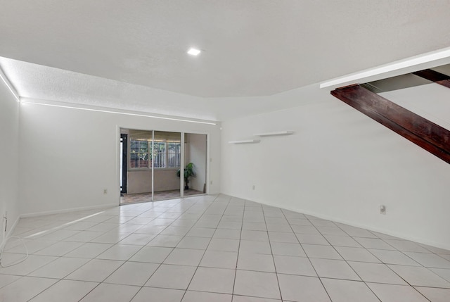 tiled empty room featuring a textured ceiling