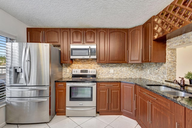 kitchen featuring light tile patterned flooring, dark stone countertops, sink, and appliances with stainless steel finishes