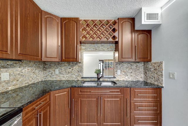 kitchen featuring a textured ceiling, backsplash, dark stone counters, and sink