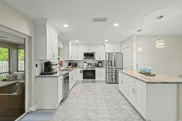 kitchen with sink, hanging light fixtures, tasteful backsplash, white cabinetry, and stainless steel appliances