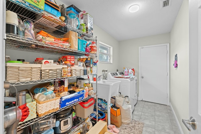 laundry room featuring sink, light tile patterned floors, a textured ceiling, and washing machine and clothes dryer