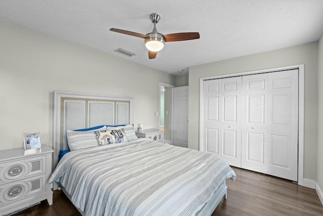 bedroom with a textured ceiling, dark hardwood / wood-style flooring, a closet, and ceiling fan