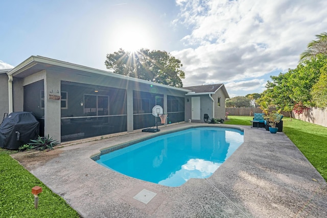 view of swimming pool with a lawn, a grill, a sunroom, and a patio area