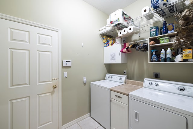 laundry room with light tile patterned floors, washer and clothes dryer, and cabinets