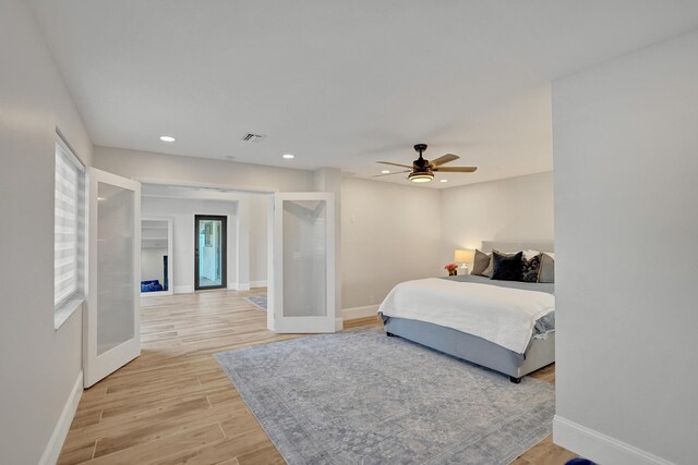 bedroom featuring ceiling fan, light hardwood / wood-style flooring, and french doors