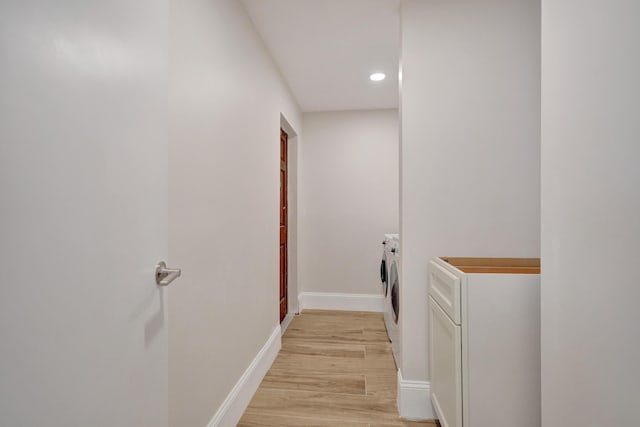 laundry area featuring washing machine and clothes dryer and light hardwood / wood-style floors