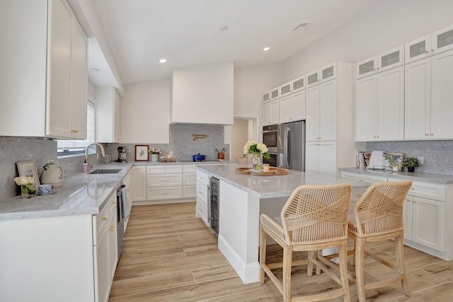 kitchen with white cabinetry, a kitchen breakfast bar, light hardwood / wood-style floors, a kitchen island, and appliances with stainless steel finishes