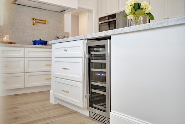 kitchen featuring light hardwood / wood-style floors, white cabinetry, and wine cooler