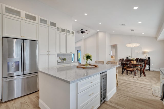 kitchen featuring white cabinets, stainless steel refrigerator with ice dispenser, a center island, and lofted ceiling