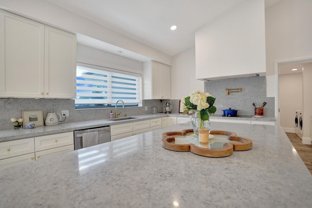 kitchen with washer and clothes dryer, dishwasher, white cabinets, sink, and tasteful backsplash