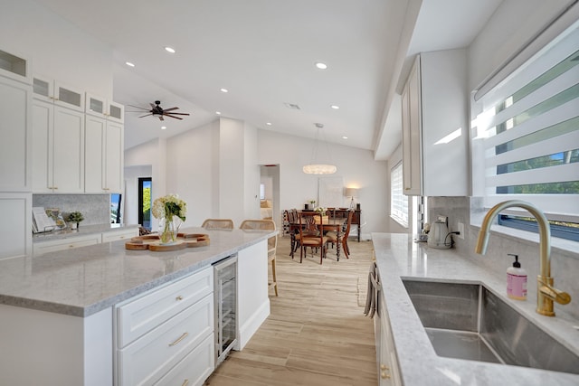 kitchen featuring white cabinetry, sink, tasteful backsplash, decorative light fixtures, and light wood-type flooring