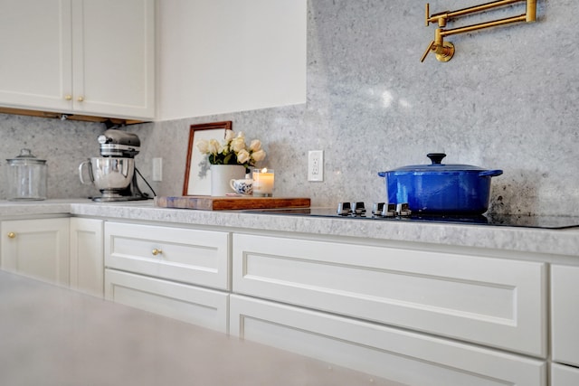 kitchen featuring white cabinets, black electric stovetop, and backsplash