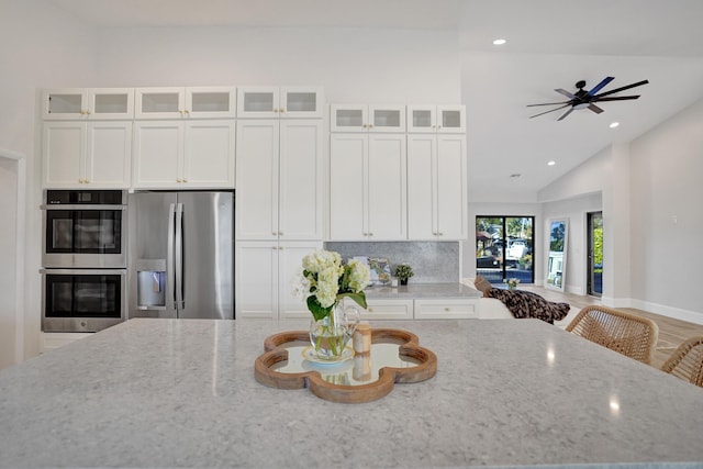 kitchen featuring white cabinets, stainless steel appliances, light stone countertops, and lofted ceiling