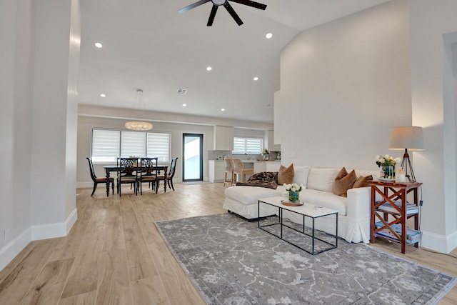 living room featuring vaulted ceiling, light hardwood / wood-style flooring, and ceiling fan