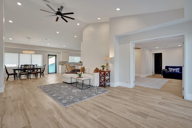 living room with light wood-type flooring, ceiling fan, and lofted ceiling