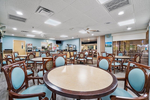 dining area with a paneled ceiling, ceiling fan, and hardwood / wood-style flooring