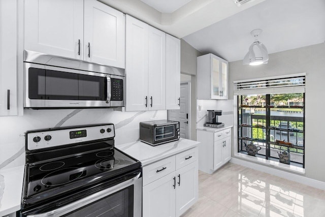 kitchen featuring backsplash, stainless steel appliances, white cabinets, hanging light fixtures, and light tile patterned flooring