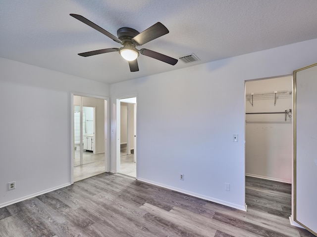 unfurnished bedroom with a closet, ceiling fan, hardwood / wood-style floors, and a textured ceiling