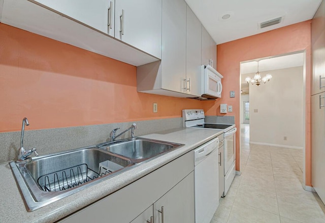 kitchen with white appliances, sink, light tile patterned floors, decorative light fixtures, and an inviting chandelier