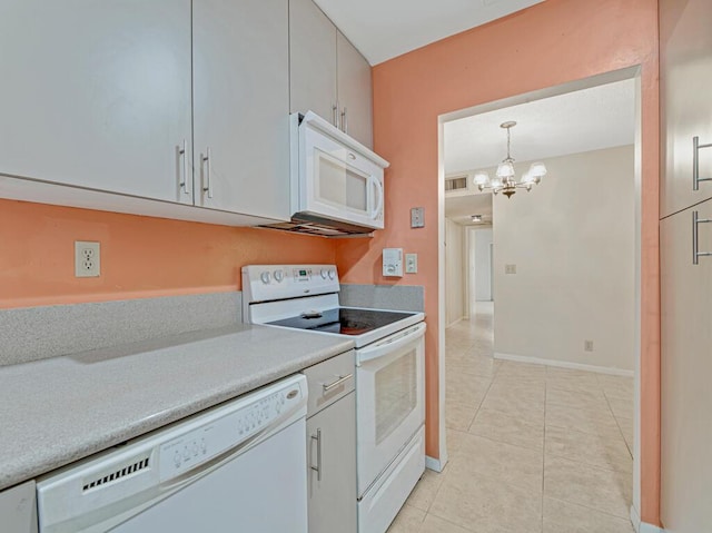 kitchen featuring light tile patterned floors, white appliances, decorative light fixtures, and an inviting chandelier