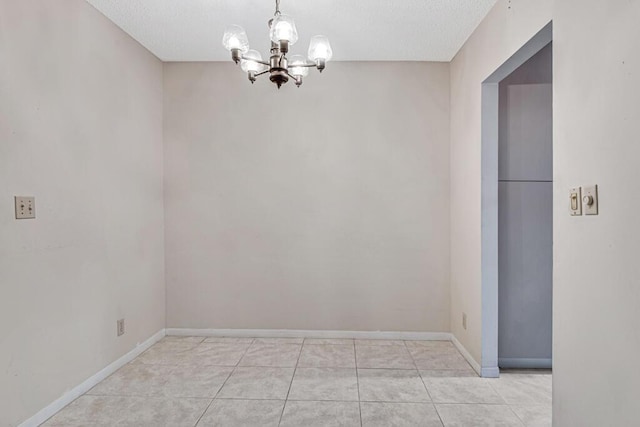 unfurnished dining area with a notable chandelier, light tile patterned flooring, and a textured ceiling