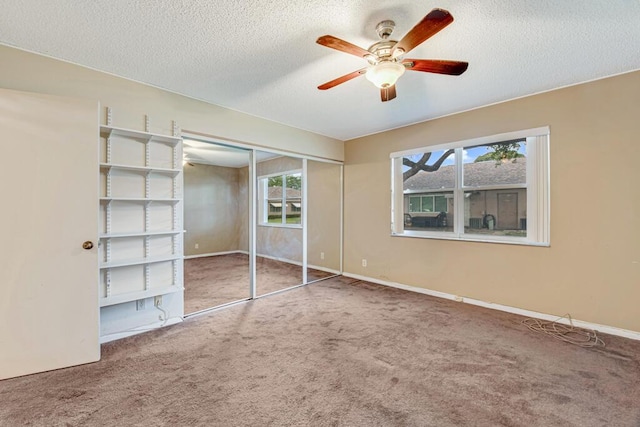 unfurnished bedroom featuring carpet, a textured ceiling, a closet, and ceiling fan