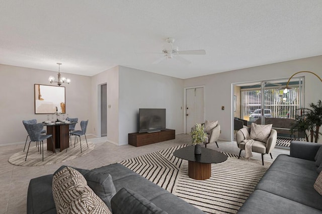 tiled living room featuring ceiling fan with notable chandelier and a textured ceiling