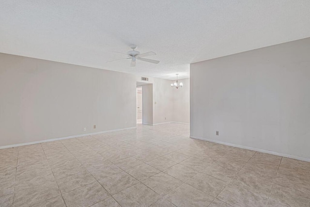 tiled spare room featuring ceiling fan with notable chandelier and a textured ceiling