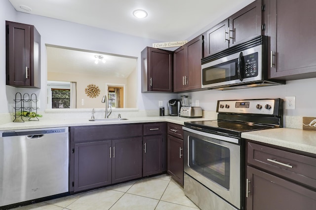 kitchen featuring light tile patterned flooring, dark brown cabinets, stainless steel appliances, and sink