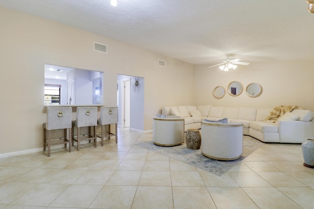 living room featuring ceiling fan, light tile patterned floors, and a textured ceiling