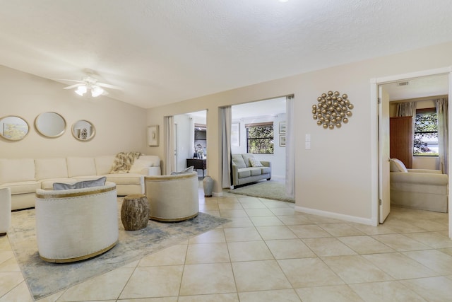 living room featuring a textured ceiling, ceiling fan, light tile patterned floors, and lofted ceiling